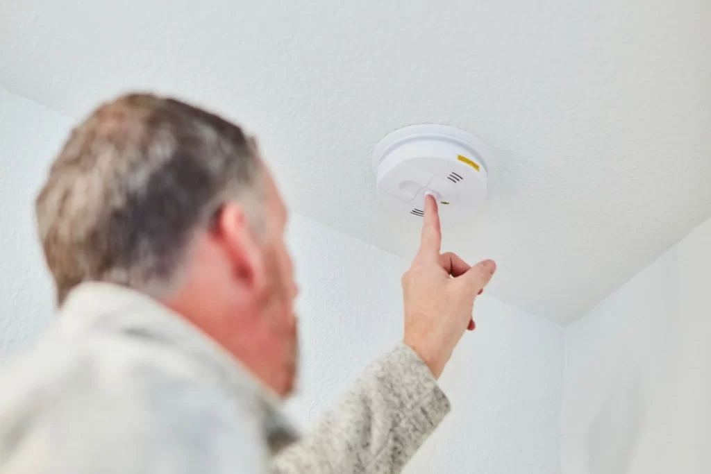 Homeowner pressing the test button on the detector unit as part of monthly testing