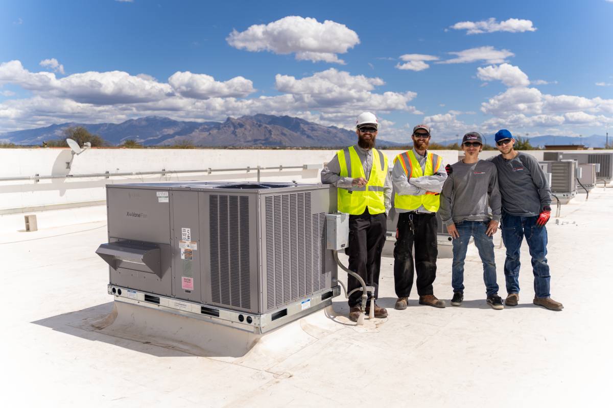 Done Rite Services team standing beside a newly installed air conditioner on a commercial rooftop in South Tucson.