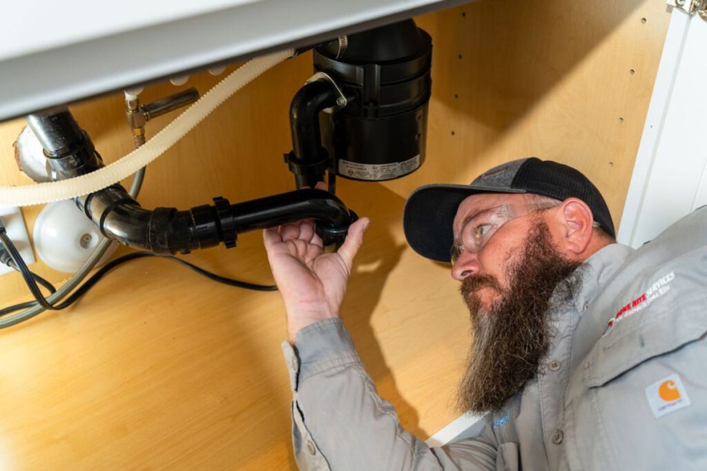 Done Rite Services expert plumber working on a garbage disposal repair, part of essential kitchen plumbing maintenance.