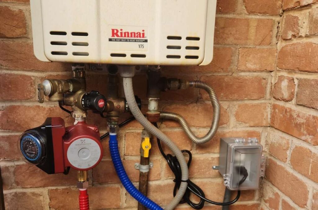 Close-up of a tankless water heater with emergency shut-off valves and connected piping.