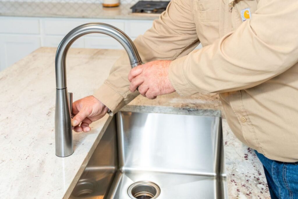 Done Rite Services expert plumber repairing a dripping faucet in a kitchen sink.