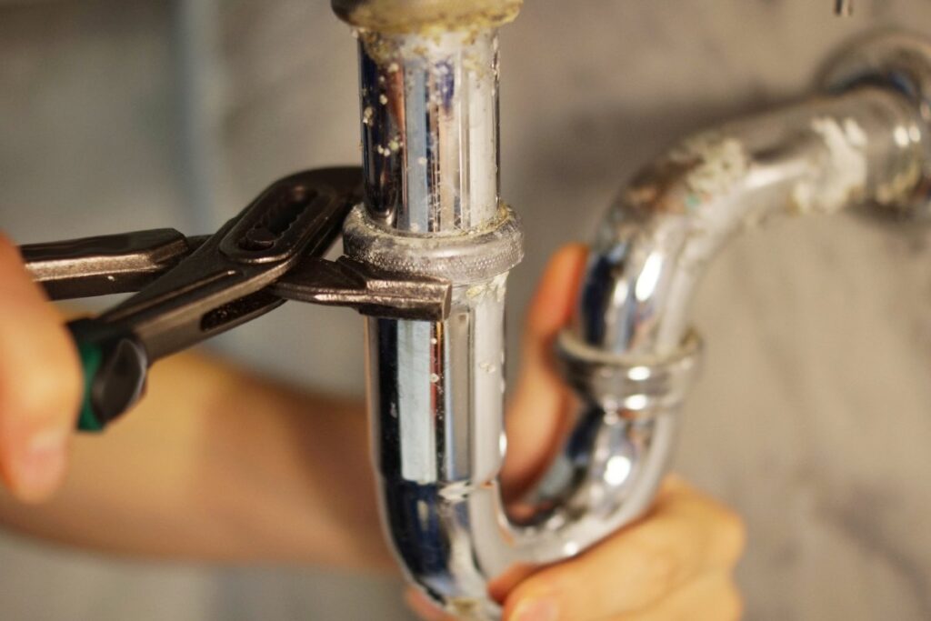 Close-up of a broken water pipe under the sink during professional plumbing repair.