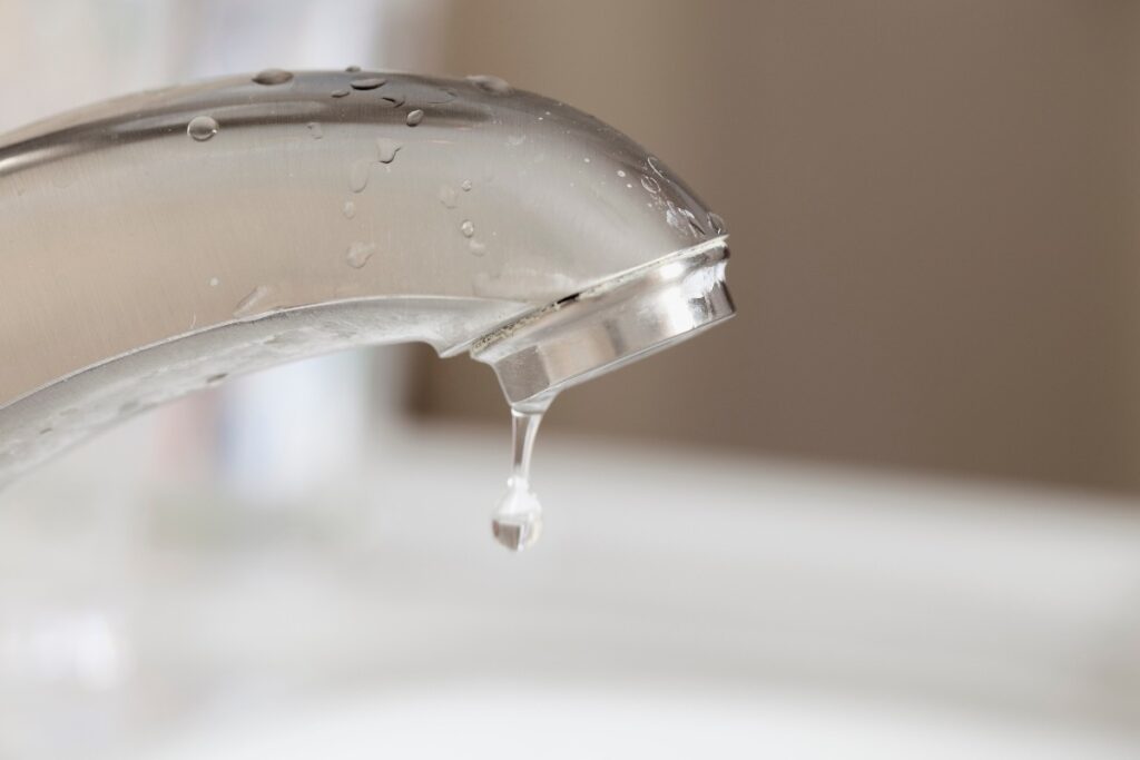 Close-up image of a dripping faucet, illustrating a common household plumbing issue.