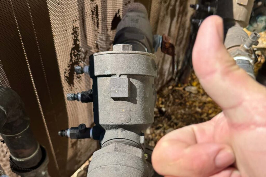 Thumbs-up in front of Tucson plumbing system with a backflow preventer installed by Done Rite Services.