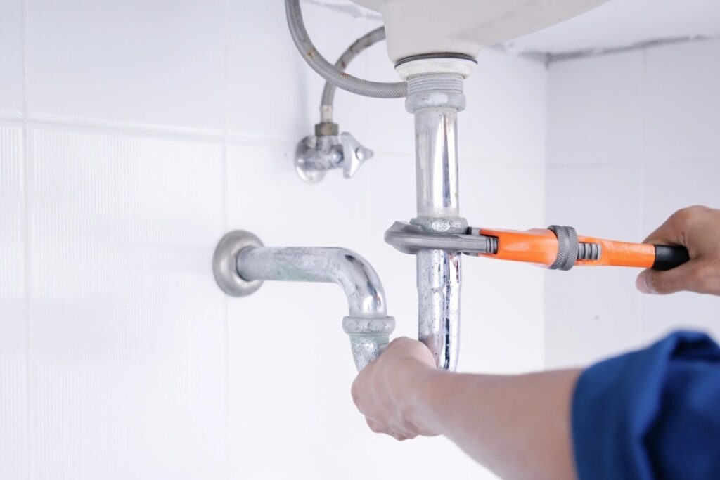 Image of Done Rite Services expert working under a sink to repair a leaking pipe.