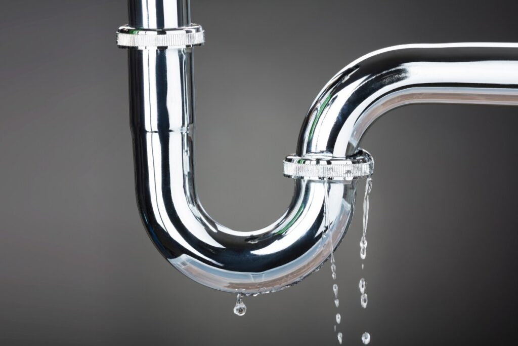 Close-up image of a plumbing pipe leaking water, showing the need for immediate plumbing repair in a Tucson home."