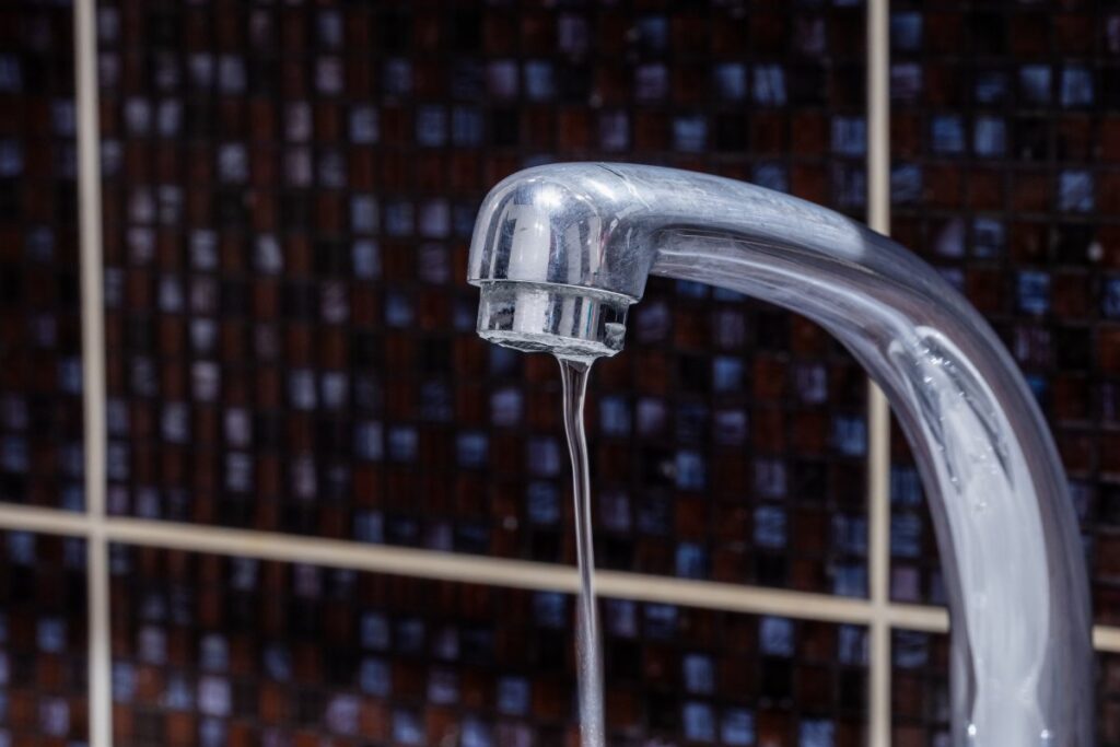 Close-up of a faucet with weak water flow, indicating low water pressure in a home plumbing system.